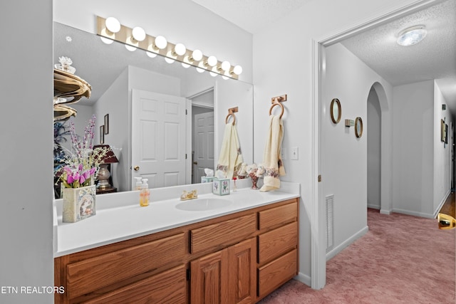 bathroom featuring vanity, baseboards, visible vents, and a textured ceiling