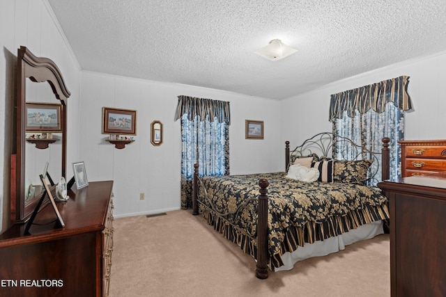 carpeted bedroom featuring a textured ceiling, visible vents, and ornamental molding