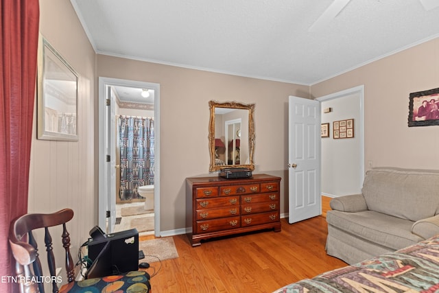 bedroom with light wood-style flooring, ornamental molding, baseboards, and ensuite bathroom
