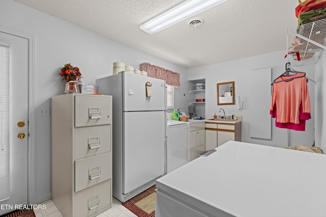 kitchen featuring a textured ceiling, light countertops, washer / clothes dryer, open shelves, and freestanding refrigerator