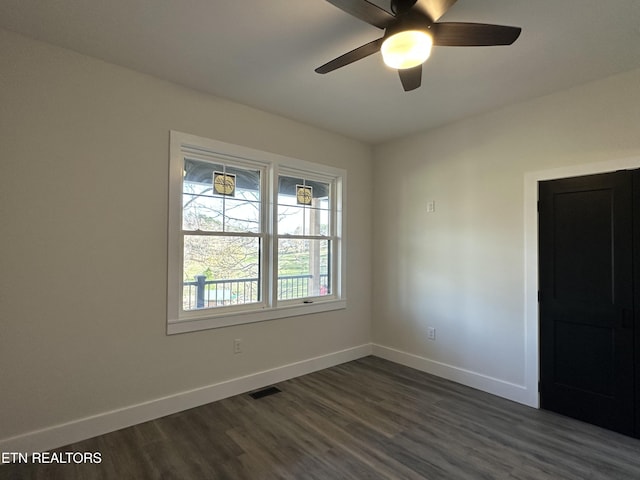 spare room with dark wood-type flooring, visible vents, baseboards, and ceiling fan