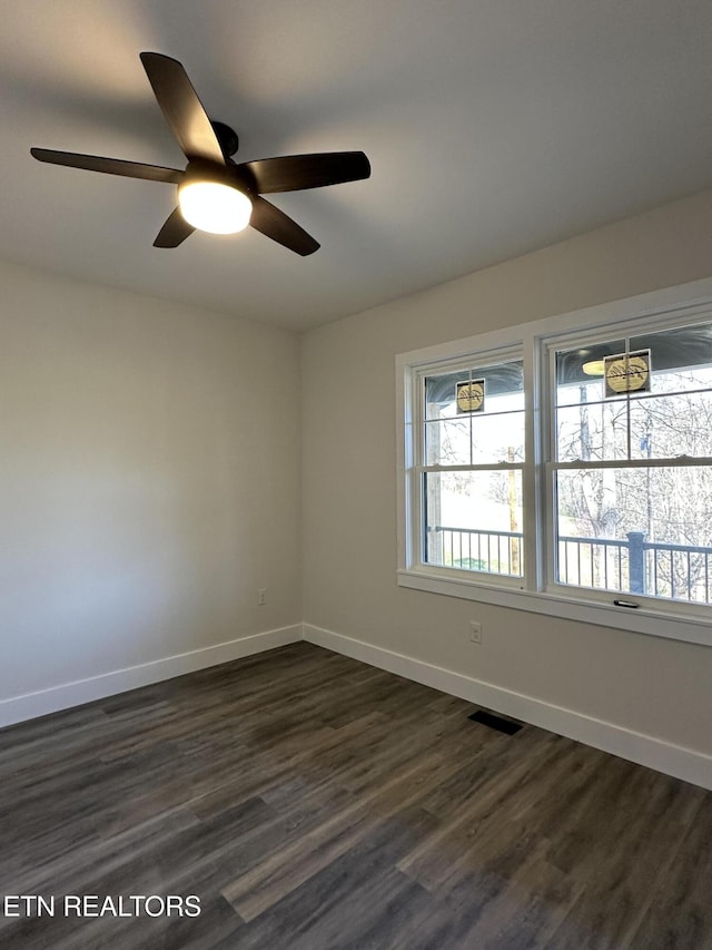unfurnished room featuring dark wood-type flooring, baseboards, a ceiling fan, and visible vents