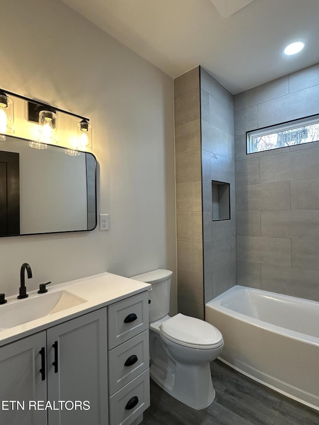 full bathroom featuring toilet, wood finished floors, vanity, and  shower combination