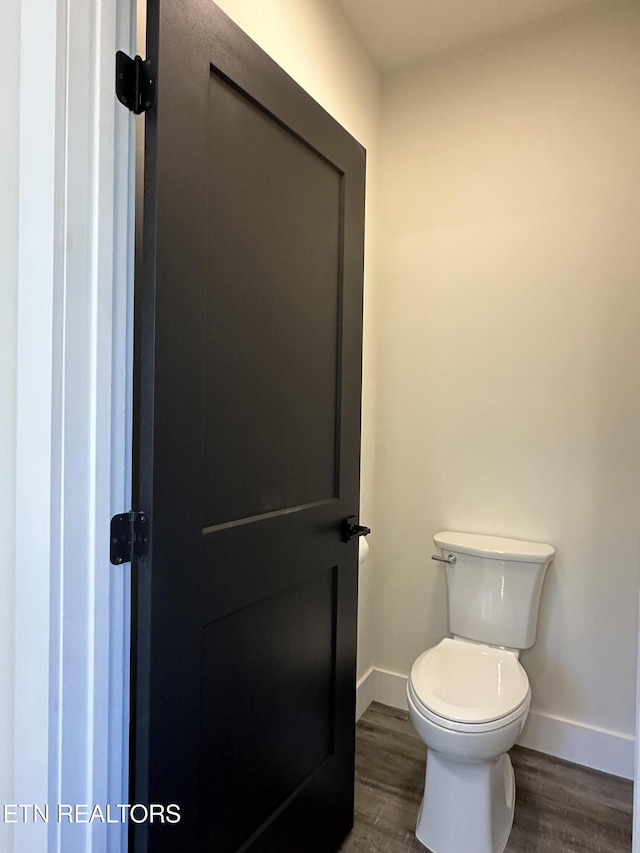 bathroom with toilet, wood finished floors, and baseboards