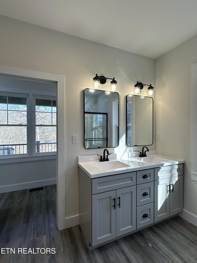 bathroom featuring baseboards, a sink, and wood finished floors