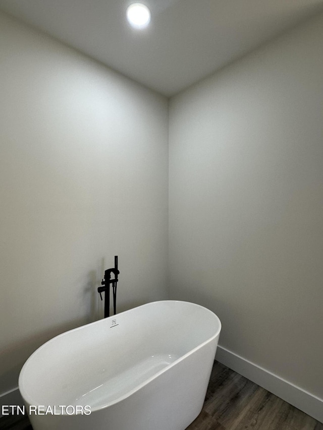 bathroom featuring baseboards, recessed lighting, a soaking tub, and wood finished floors