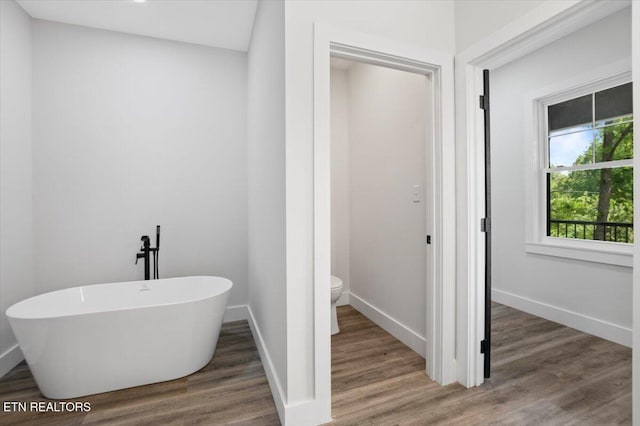 520 Ridge Rd, Caryville, TN 37714 - bathroom featuring toilet, wood finished floors, a freestanding bath, and baseboards