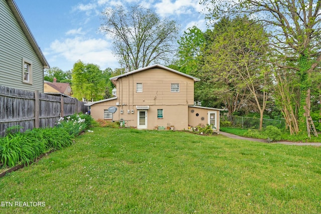back of house featuring a yard and fence