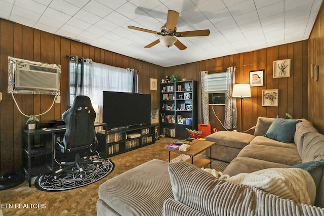 living room featuring an AC wall unit, a ceiling fan, carpet flooring, and wooden walls