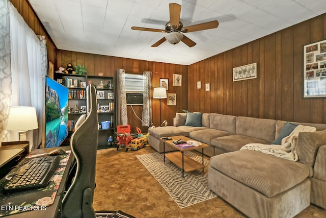 living area with ceiling fan and wooden walls