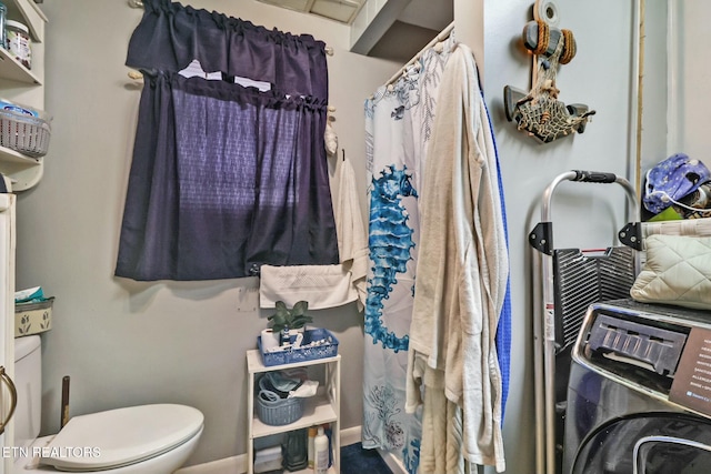 bathroom with a shower with shower curtain, washer / clothes dryer, and toilet