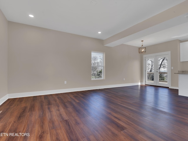 unfurnished living room with dark wood-style floors, baseboards, and a wealth of natural light