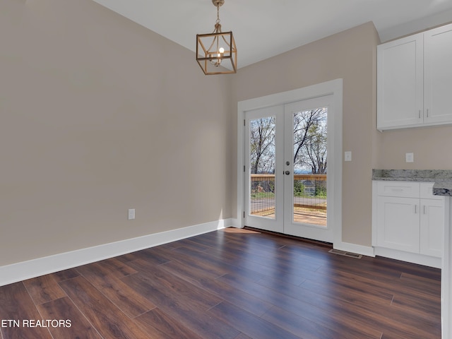 unfurnished dining area with an inviting chandelier, dark wood-style floors, french doors, and baseboards