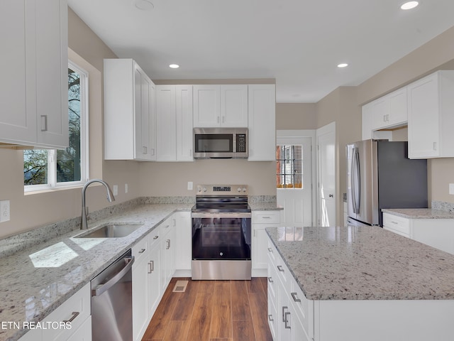 kitchen featuring wood finished floors, stainless steel appliances, recessed lighting, white cabinetry, and a sink