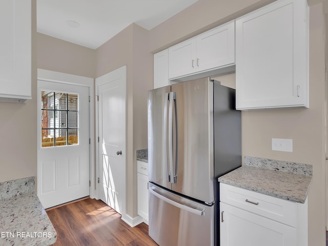 kitchen featuring freestanding refrigerator, white cabinets, dark wood-style flooring, and light stone counters