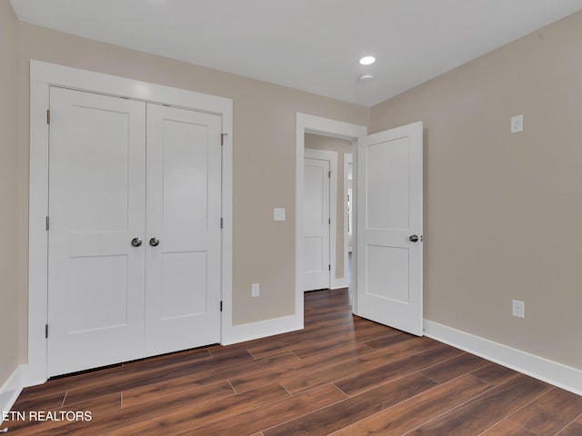 unfurnished bedroom featuring baseboards, a closet, and dark wood-style flooring