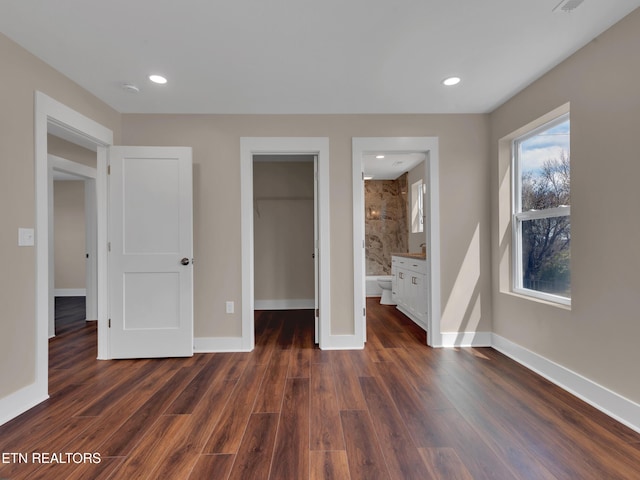 unfurnished bedroom with baseboards, a walk in closet, recessed lighting, and dark wood-type flooring