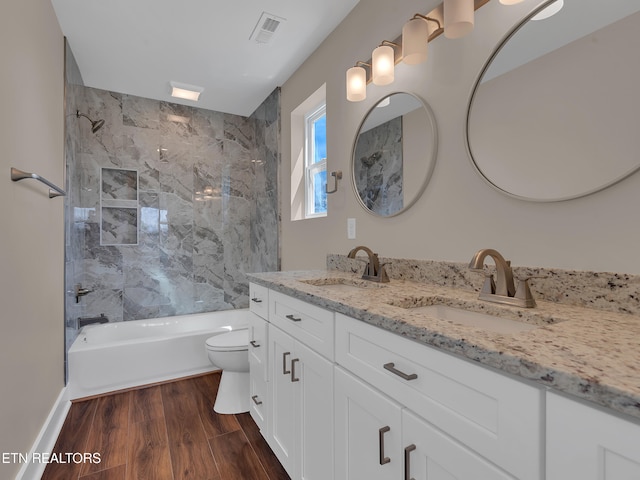bathroom featuring wood finished floors, a sink, toilet, and visible vents