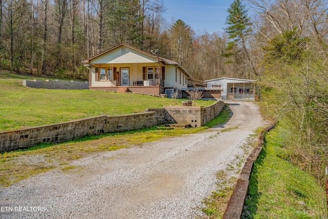 275 White Oak Rd, Oakdale, TN 37829 - view of front facade featuring covered porch, a wooded view, gravel driveway, and a front lawn