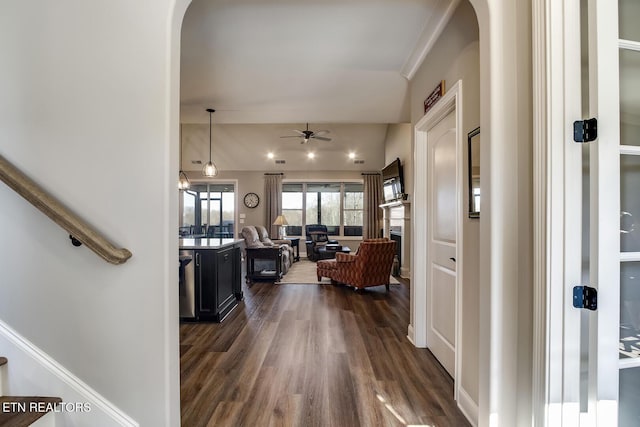 hallway featuring arched walkways, vaulted ceiling, and dark wood-type flooring