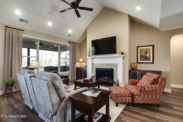 living room with dark wood-style floors, ceiling fan, visible vents, and a premium fireplace