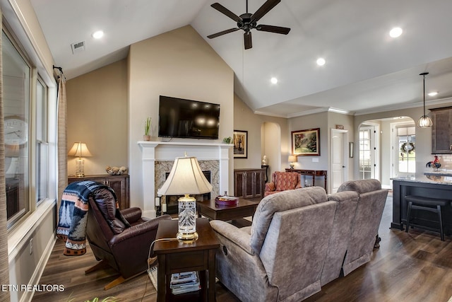 living area with visible vents, arched walkways, a premium fireplace, and ceiling fan