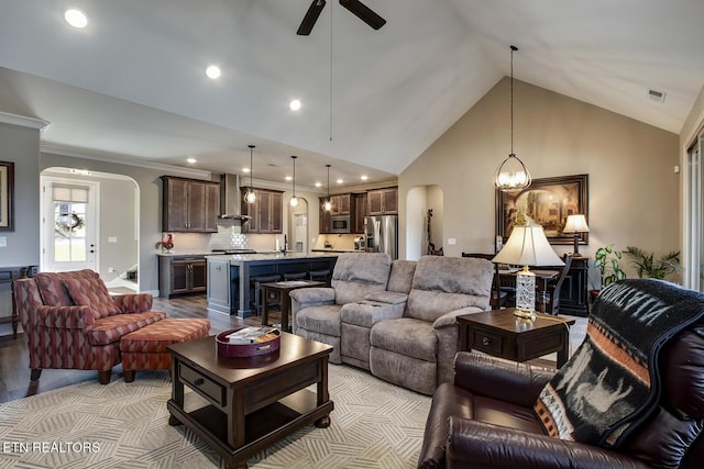 living area featuring ceiling fan with notable chandelier, visible vents, high vaulted ceiling, and arched walkways