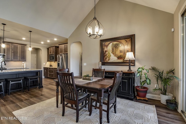 dining room with high vaulted ceiling, a chandelier, dark wood finished floors, arched walkways, and recessed lighting