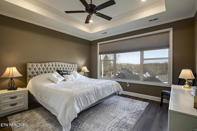 bedroom featuring dark wood-style floors, visible vents, baseboards, and a raised ceiling