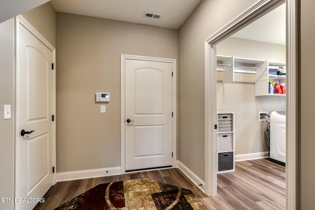 foyer with baseboards, washing machine and dryer, visible vents, and wood finished floors