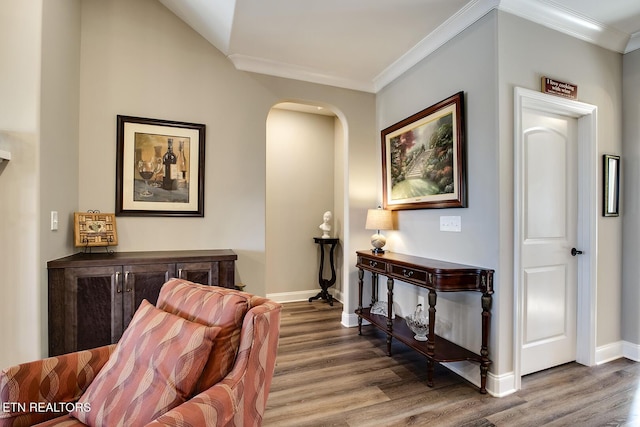 sitting room featuring arched walkways, baseboards, wood finished floors, and crown molding