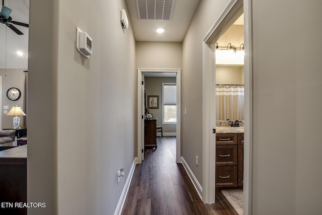 hall featuring dark wood-style floors, baseboards, and visible vents