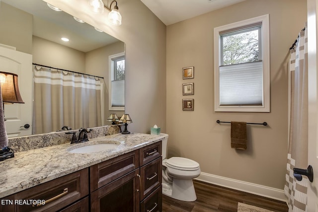bathroom featuring baseboards, wood finished floors, toilet, and vanity