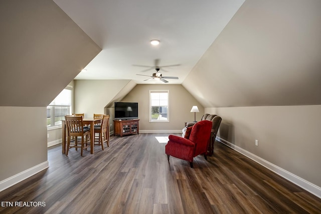 living area featuring baseboards, lofted ceiling, and dark wood finished floors