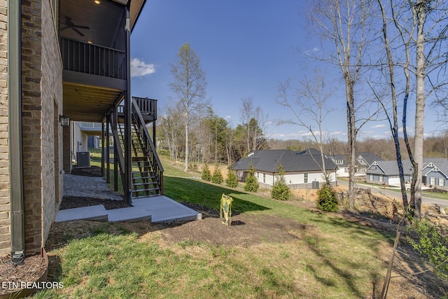 view of yard featuring stairway, a ceiling fan, and a residential view