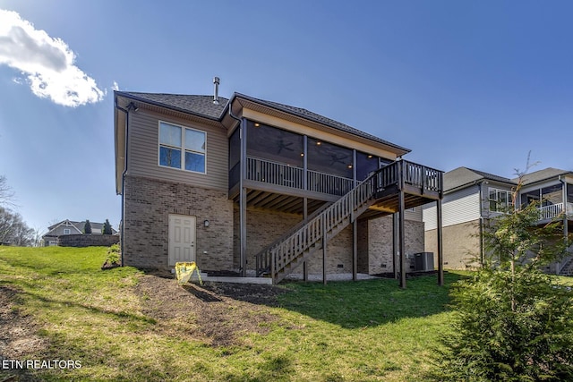 rear view of house featuring a sunroom, central air condition unit, stairway, brick siding, and a lawn