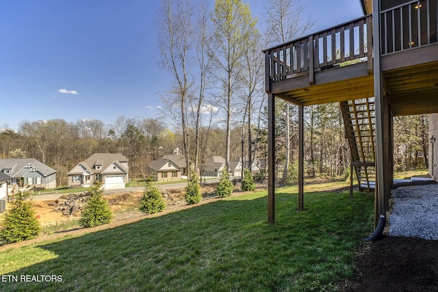 view of yard featuring a residential view, a wooden deck, a garage, and stairway