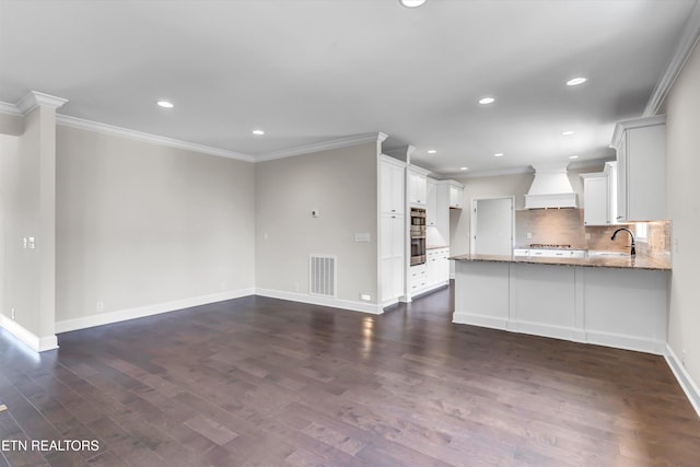 kitchen with visible vents, a sink, ornamental molding, light stone countertops, and custom range hood