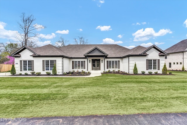 ranch-style house featuring roof with shingles and a front lawn