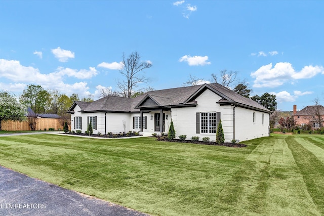 ranch-style home with a front yard and fence