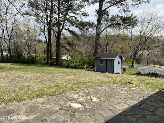 view of yard with an outdoor structure, fence, and a storage shed