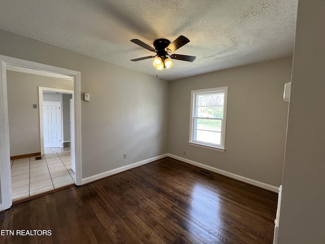 unfurnished room featuring wood finished floors, a textured ceiling, baseboards, visible vents, and ceiling fan