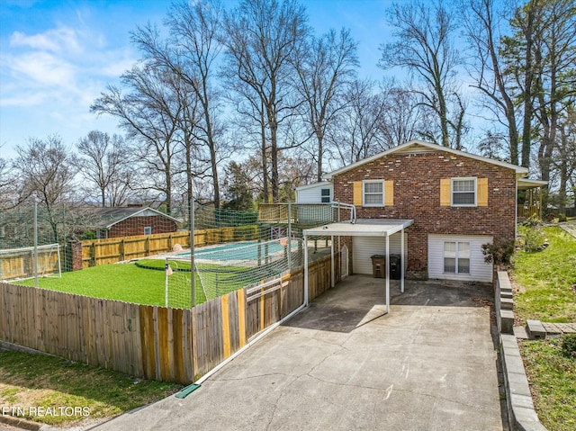 exterior space with driveway, brick siding, a front lawn, a carport, and fence private yard