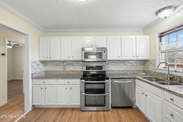 kitchen featuring light wood finished floors, white cabinetry, a sink, and stainless steel appliances