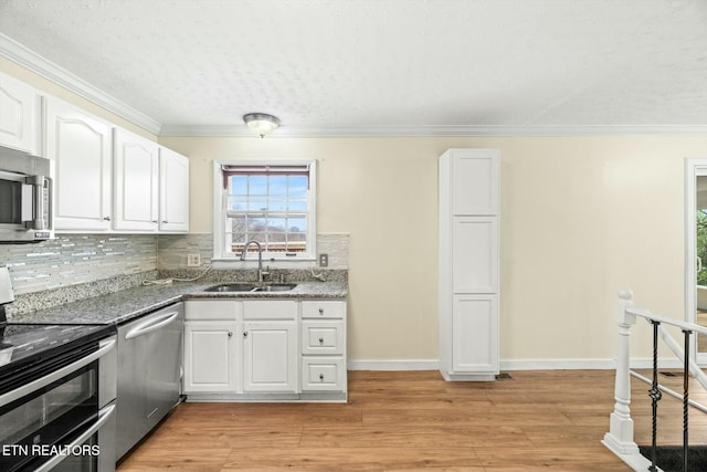 kitchen with backsplash, white cabinets, a sink, and stainless steel appliances