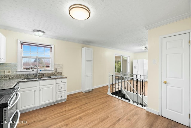 kitchen featuring stainless steel range with electric stovetop, a sink, light wood finished floors, white cabinets, and white fridge with ice dispenser