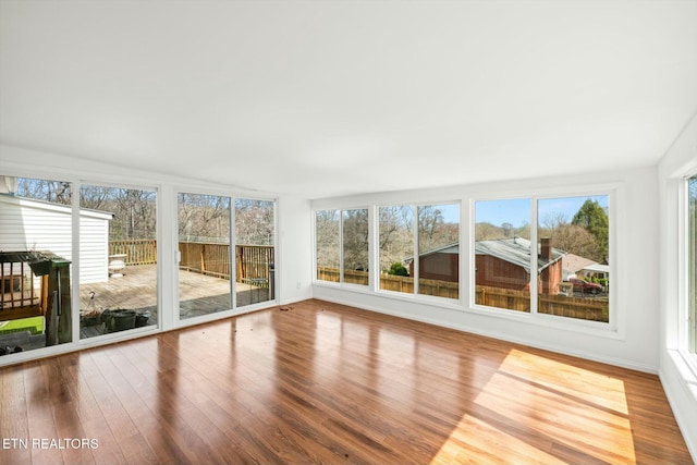 unfurnished sunroom with plenty of natural light, baseboards, and wood finished floors