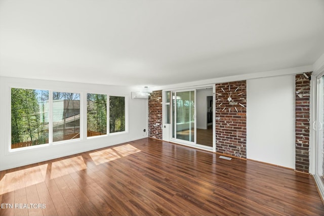interior space with a wall mounted AC, wood finished floors, and brick wall
