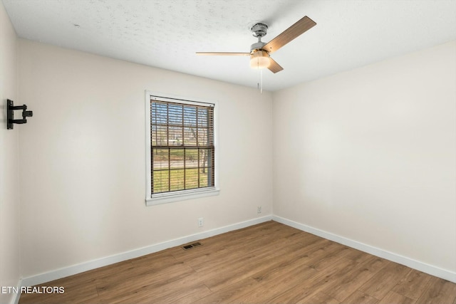 unfurnished room with wood finished floors, a textured ceiling, baseboards, visible vents, and ceiling fan