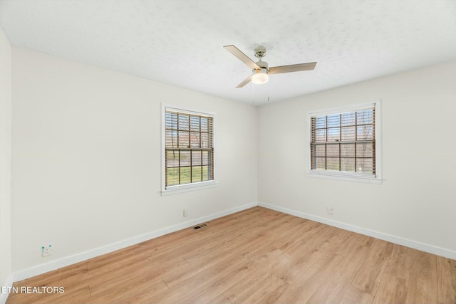spare room featuring plenty of natural light, baseboards, visible vents, and light wood-style floors